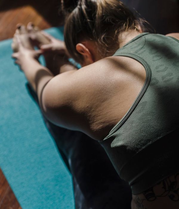 Woman in a calm, focused stretching pose in a dark room.